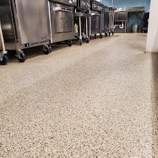 Commercial kitchen floor with a tan flake coating beneath stainless steel equipment
