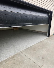 Two-car garage with a gray flake-coated floor seen through an open black garage door