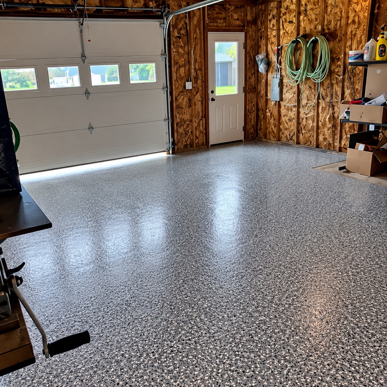 The same garage after coating: a glossy gray flake floor reflecting light from the bay door windows