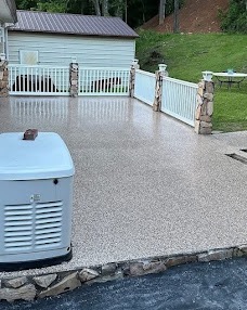 Large outdoor patio with a tan flake coating, white vinyl fence and stone pillars