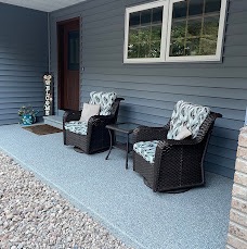 Covered front porch with a light gray flake coating and wicker chairs