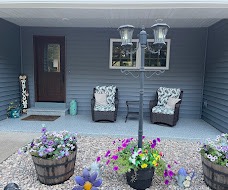 Front porch with a light gray flake coating, flower barrels and a lamp post